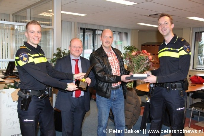 Martien van Herk (rechts) overhandigt Rob Voorbij een presentje en bloemen voor zijn inzet. Terwijl burgemeester Divendal de speciale trofee in ontvangst neemt van Peter Smit (links)